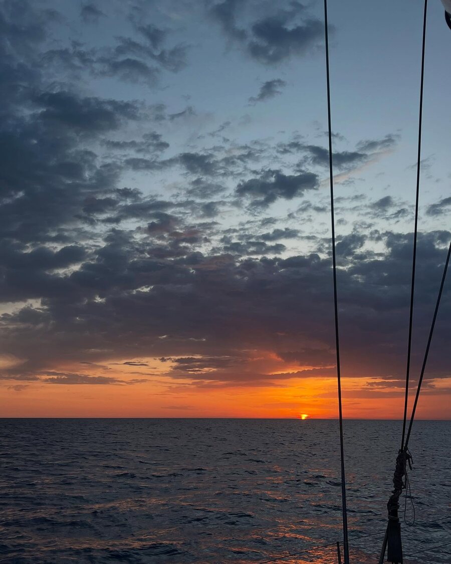 Закат над открытым морем, вид с борта яхты сквозь снасти